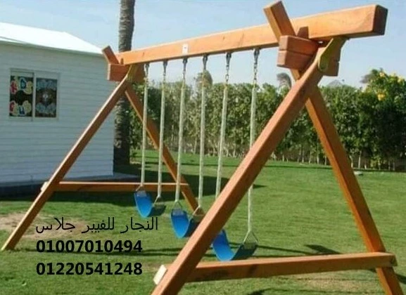 أرجوحة خشبية للحدائق تضم ثلاثة مقاعد أراجيح فيبر جلاس متينة باللون الأزرق، مثبتة بانتظام على نجيل أخضر لتوفير منطقة ترفيهية آمنة ومقاومة للعوامل الجوية مع أرقام التواصل للتجهيزات.